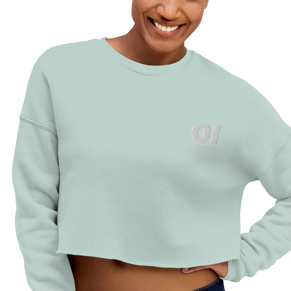 other ideas eco streetwear sustainable women's dusty blue cropped sweatshirt logo embroidered slow fashion modelled front view zoomed in showing logo detail